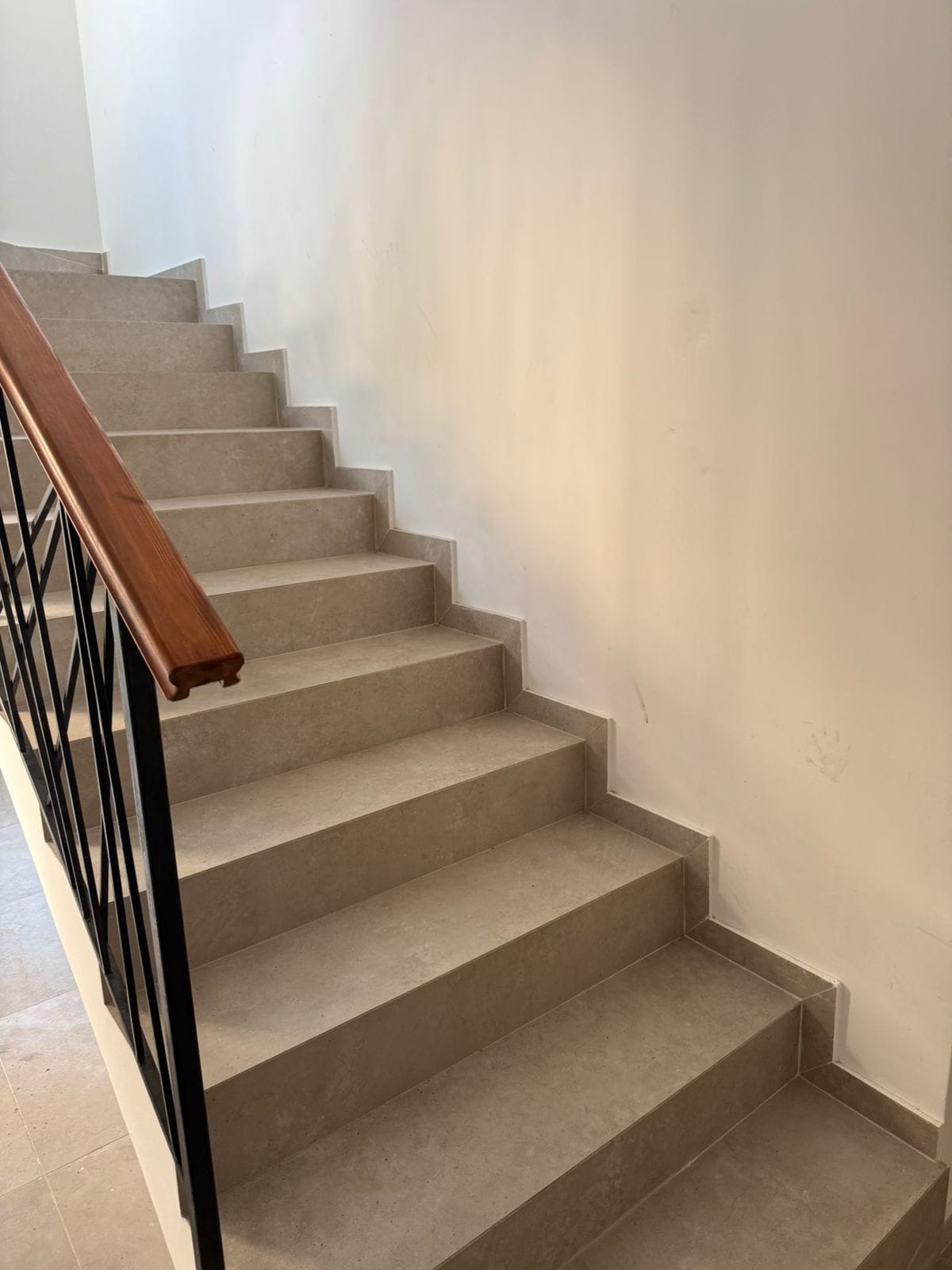 Staircase with beige tiles and wrought-iron railings in a modern apartment, Tivat, Montenegro.