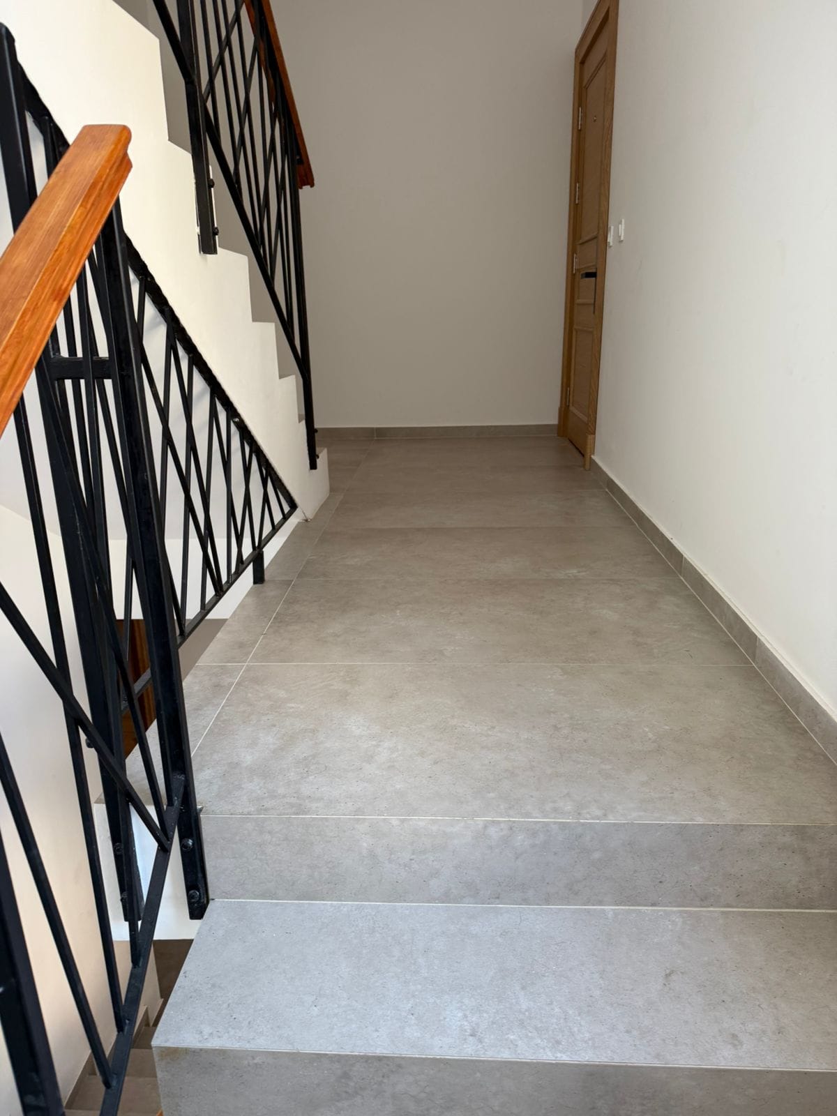 Staircase with wrought-iron railings and wooden handrails in a modern apartment, Tivat, Montenegro.