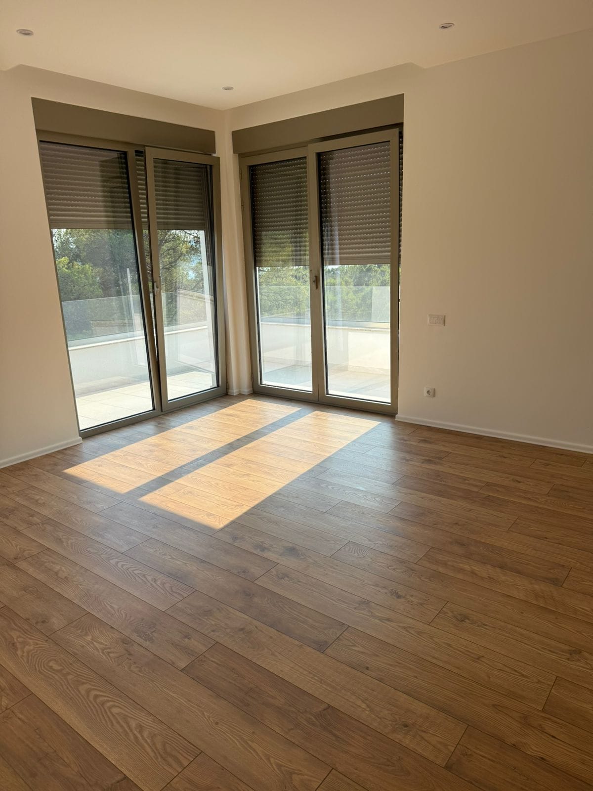 Bright living room in an apartment in Tivat, Montenegro: panoramic windows, access to the terrace, and high-quality laminate flooring.