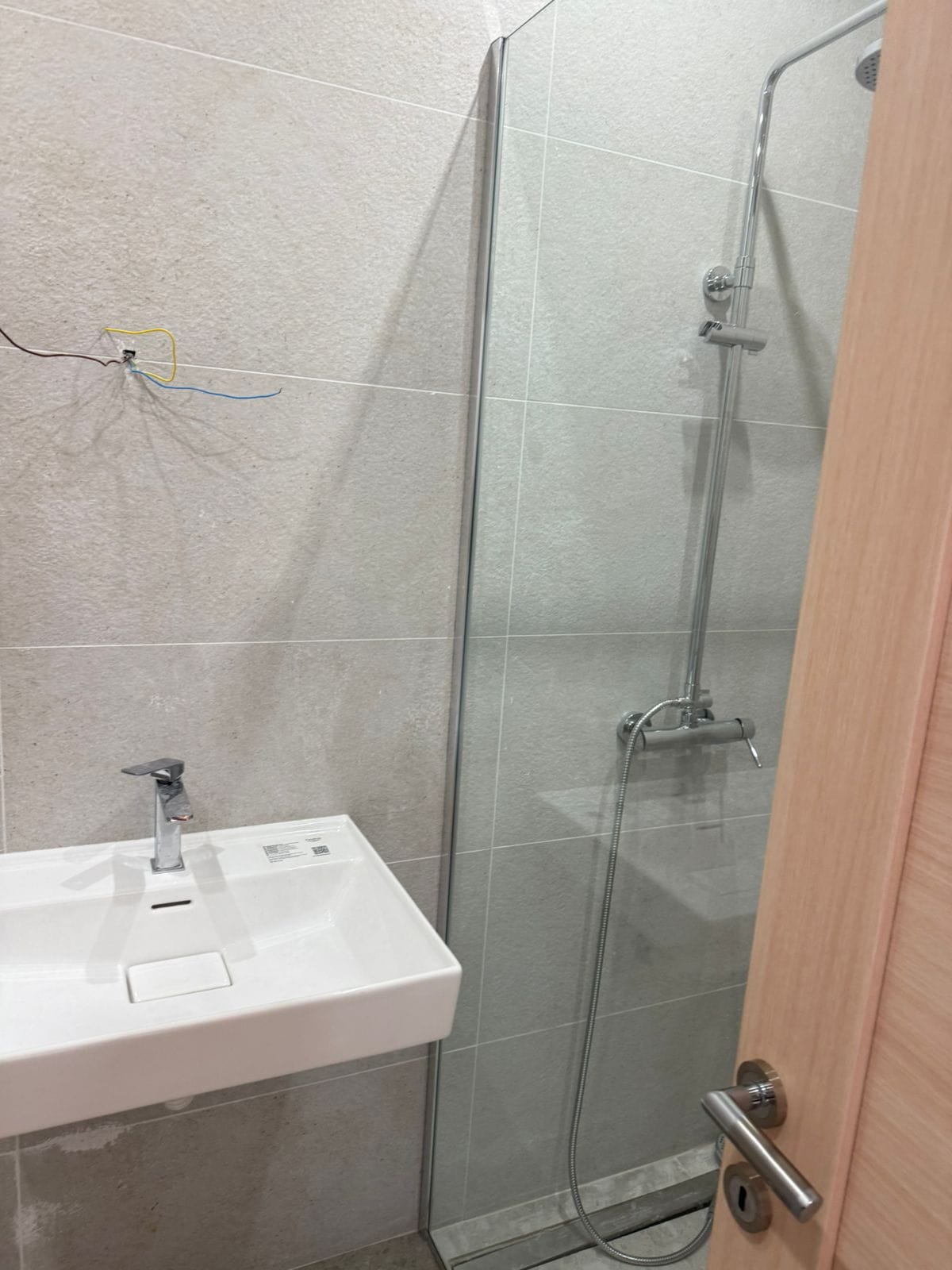 Modern bathroom in an apartment in Tivat, Montenegro: shower cabin, white sink, and tiled finish.