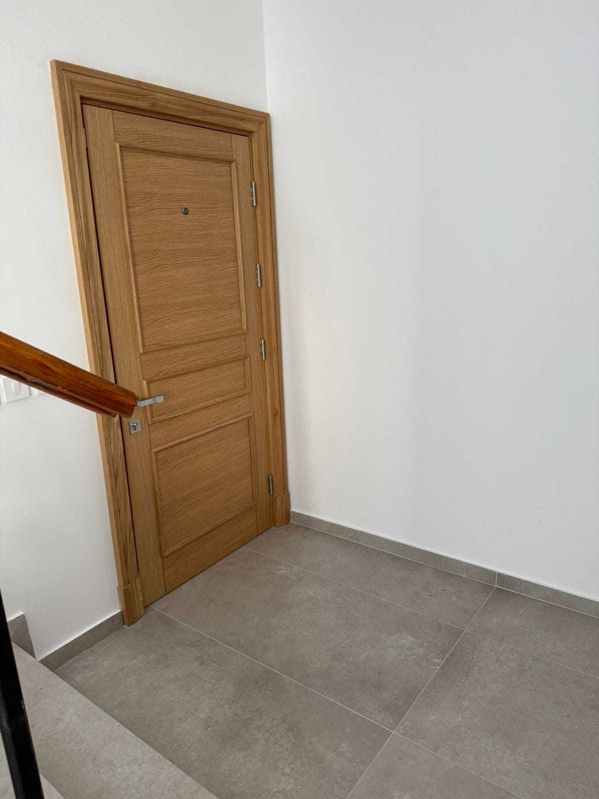 An interior door made of light wood in an apartment in Tivat, Montenegro, with porcelain tile flooring.
