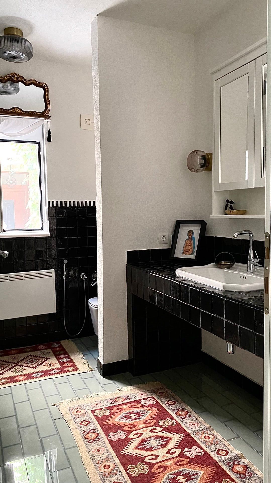 Bathroom in an apartment in Petrovac, Montenegro: black tiles, a vintage mirror, and oriental rugs in the interior.