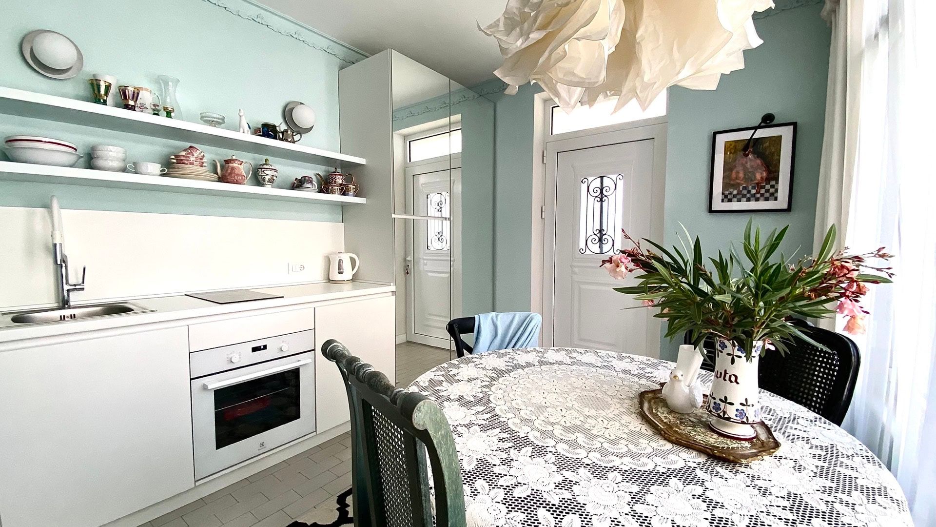 Bright kitchen in an apartment in Petrovac, Montenegro: white furniture, open shelves with decor, and a dining area.