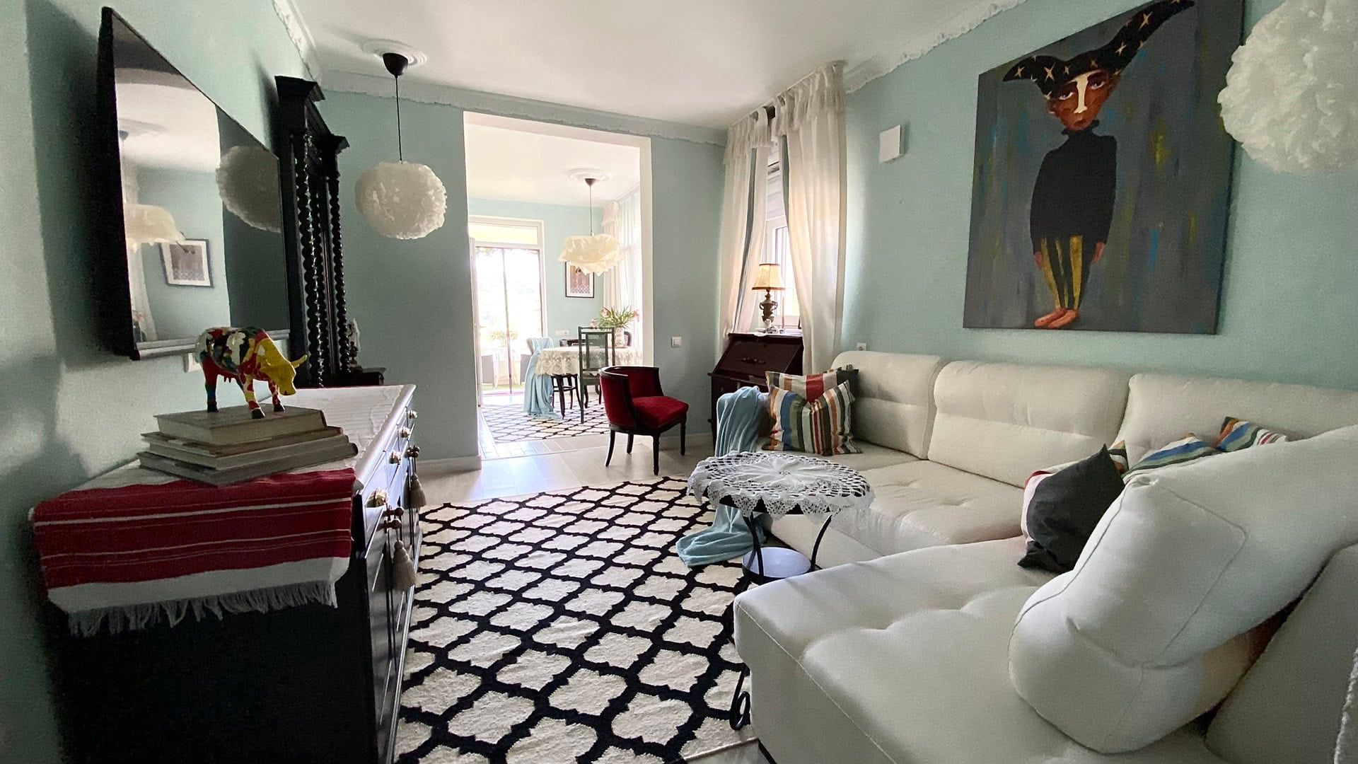 Living room with white sofa, black and white rug, and artwork on a light green wall.