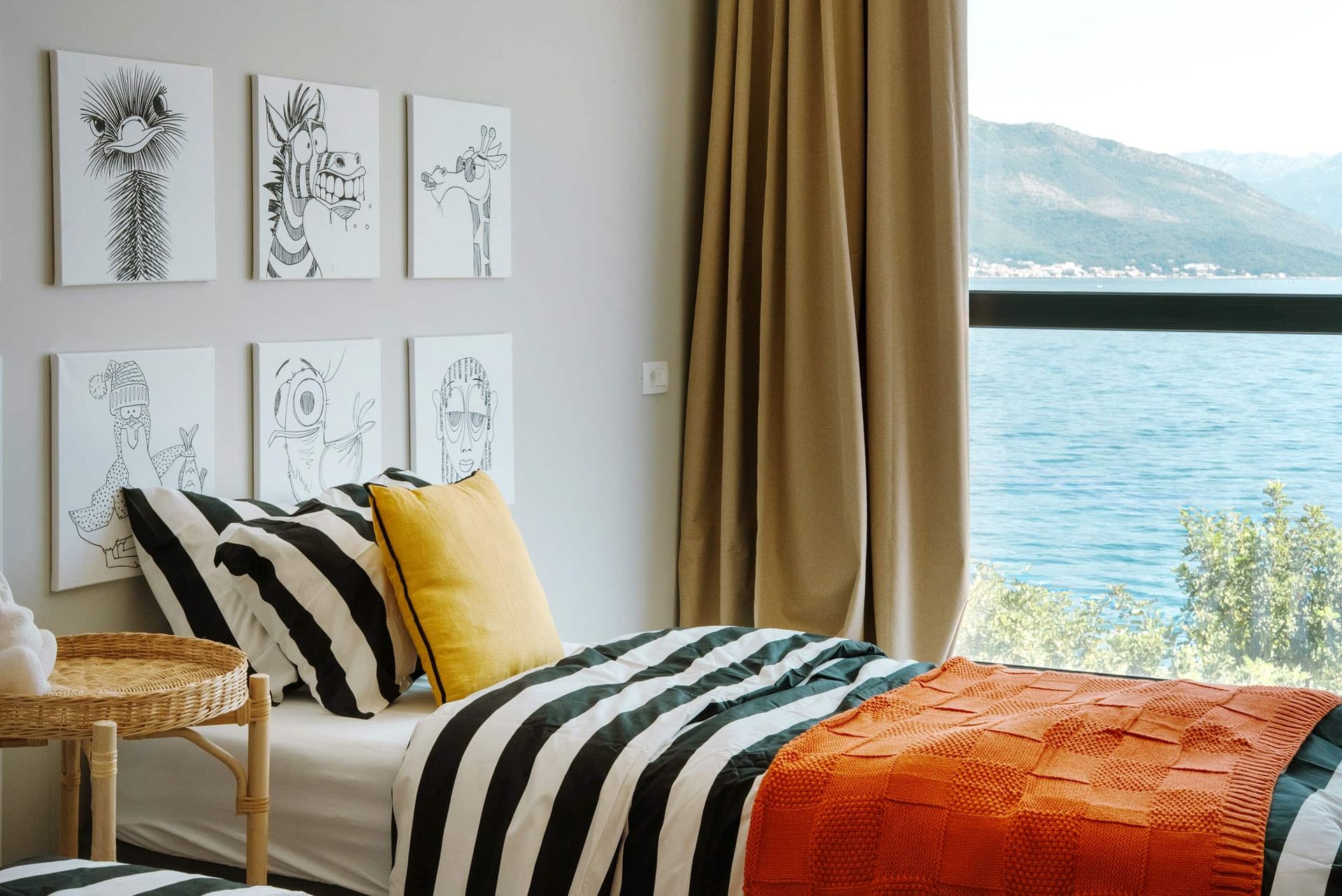Children's bedroom in a villa in Krašići, Montenegro, with a sea view, striped bed, and wall art.