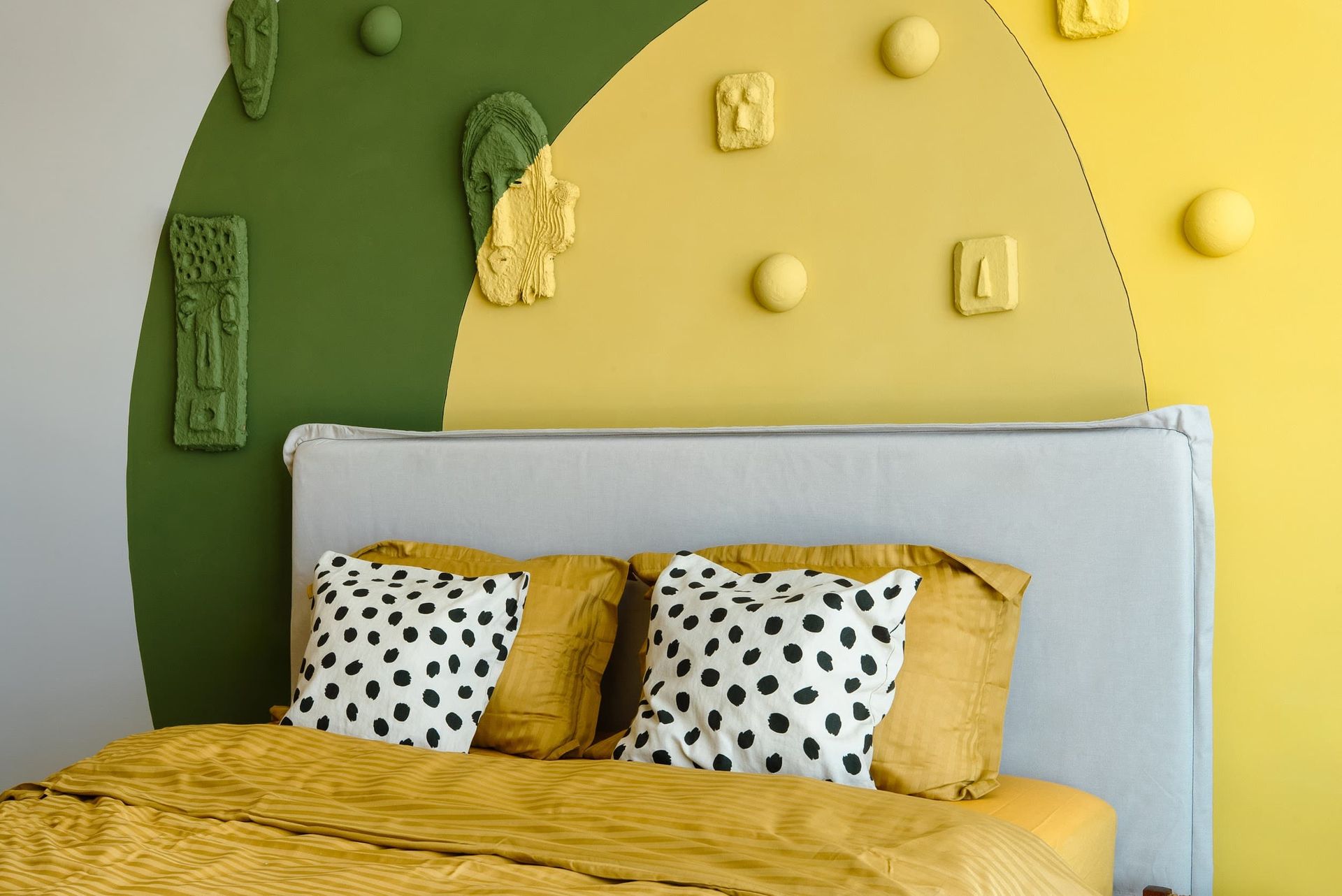 Designer bedroom with yellow-green wall decor in a villa in Krašići, Montenegro: double bed with vibrant textiles.
