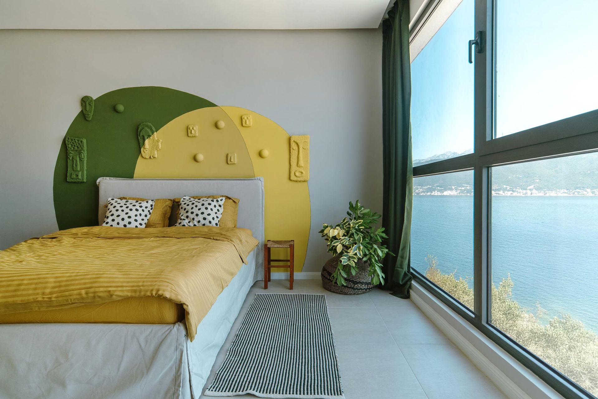 Bedroom in a villa in Krašići, Montenegro: designer accent wall, double bed, and panoramic sea view from the window.