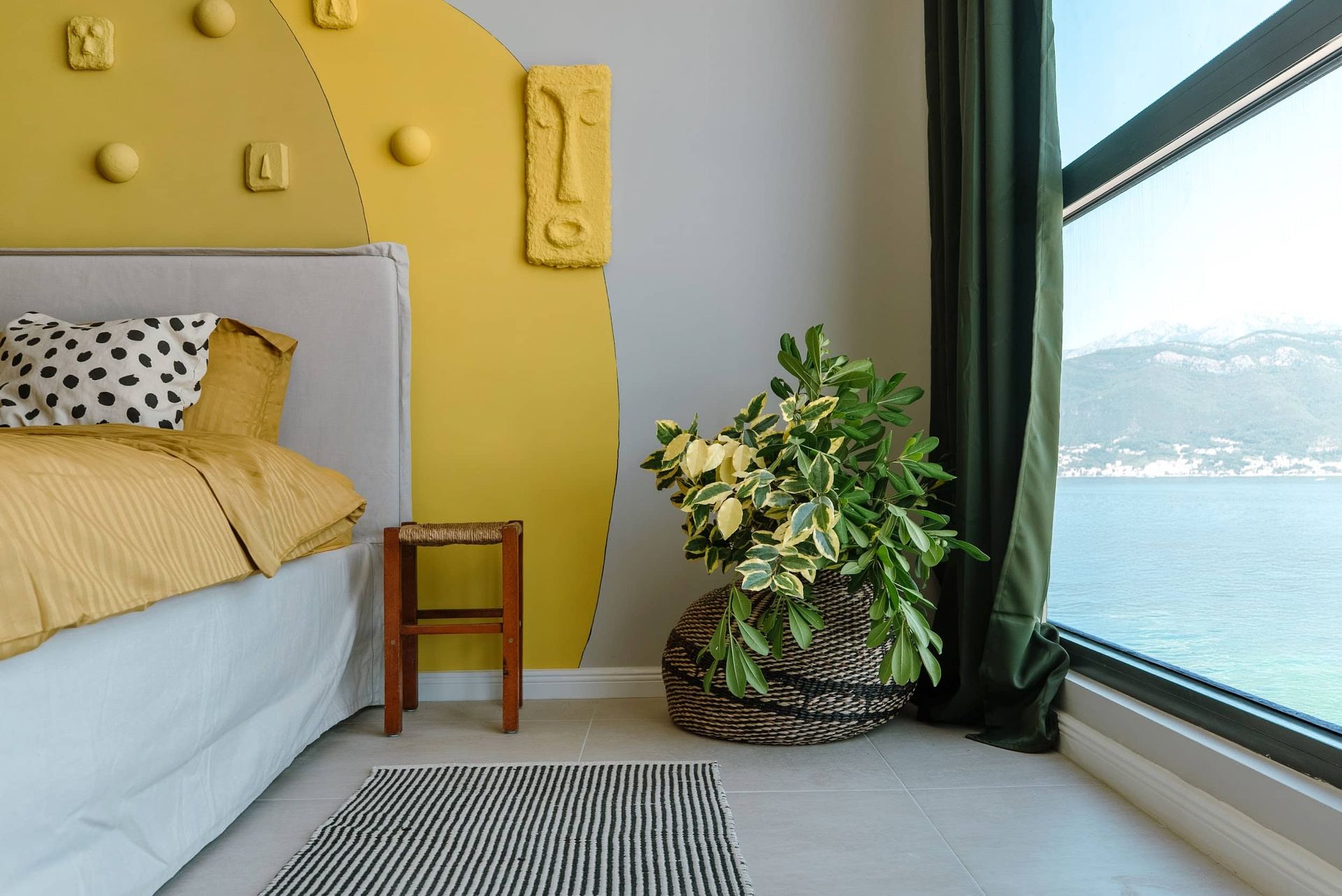 Bedroom with a sea view in a villa in Krašići, Montenegro: stylish interior, yellow decor, and panoramic windows.