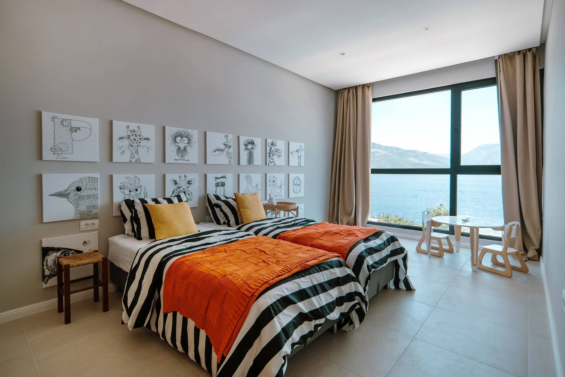 Children's bedroom with a sea view in a villa in Krašići, Montenegro: two beds, animal-themed decor, and panoramic windows.