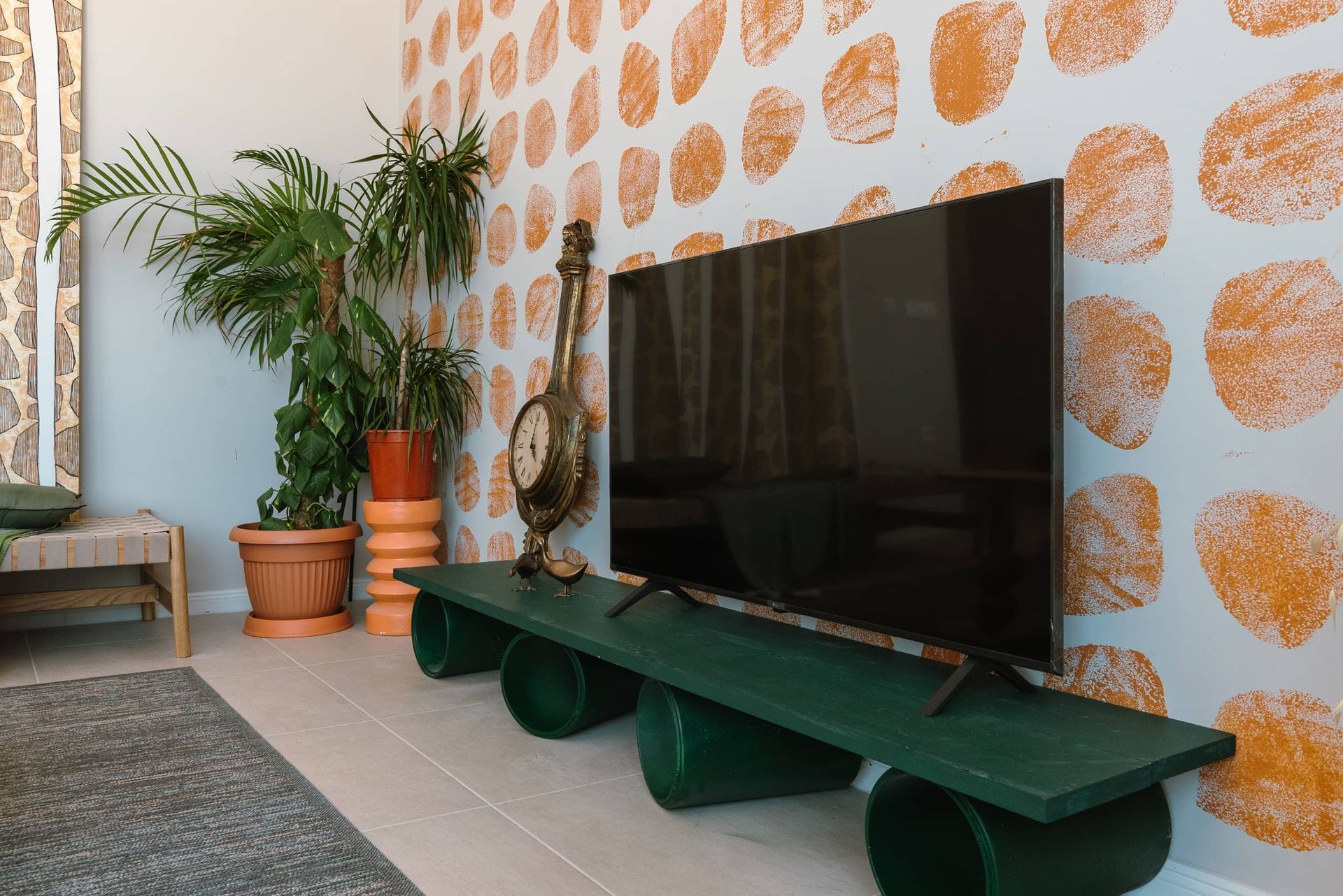 Living room of a villa in Krašići, Montenegro: TV area with a designer shelf, house plants, and vibrant wallpaper.