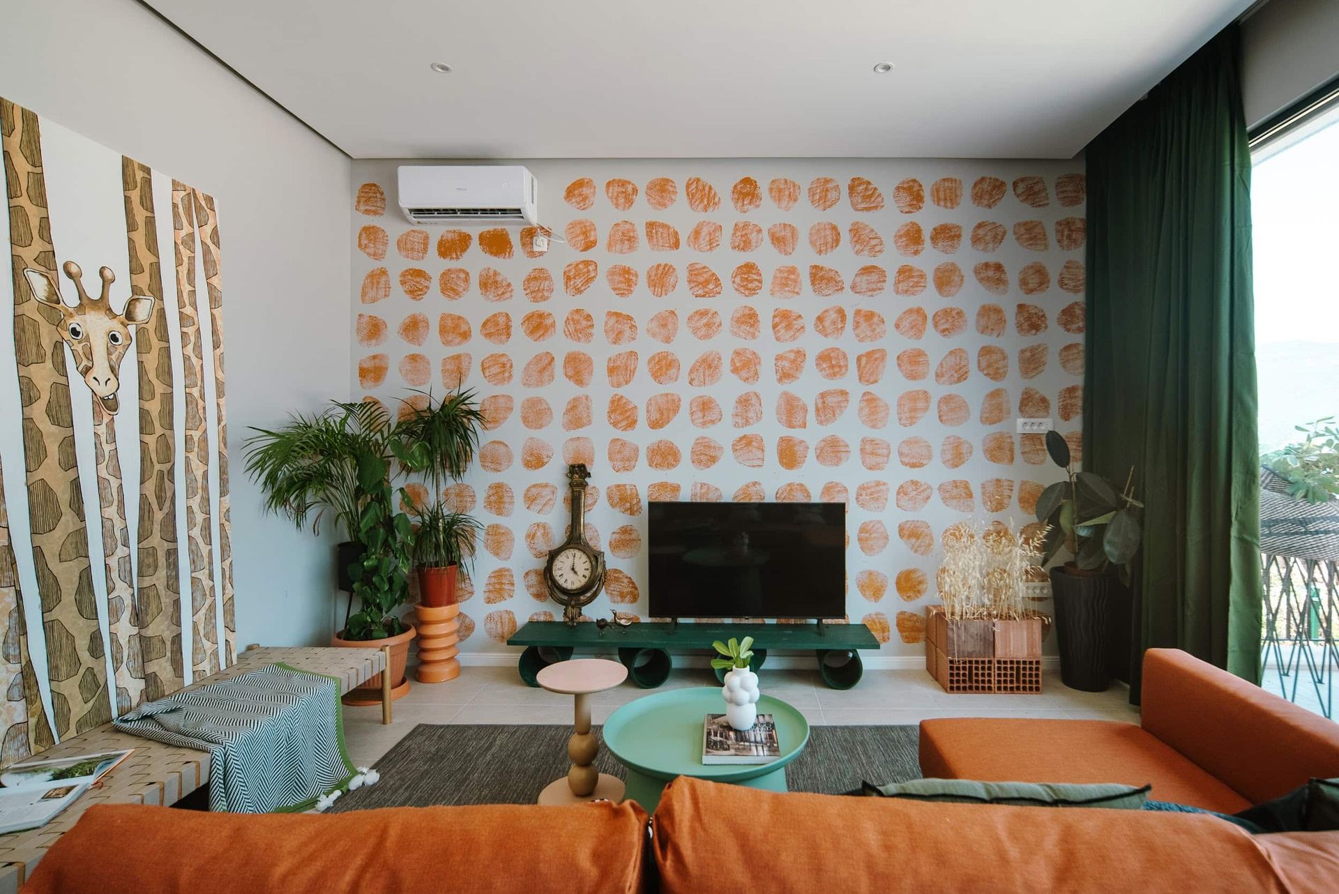 Living room of a villa in Krašići, Montenegro: designer interior with orange accents, live plants, and a TV area.