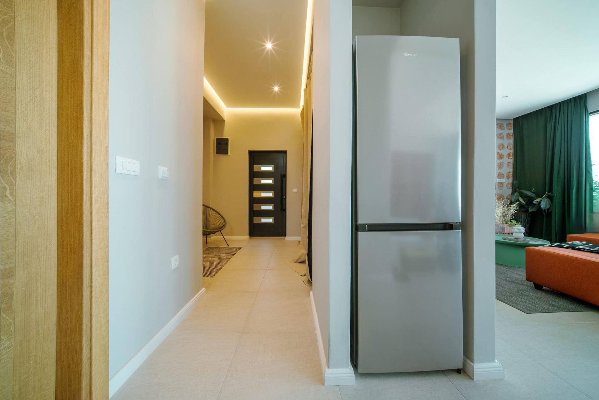 Modern villa interior in Krašići, Montenegro: hallway with ambient lighting, Gorenje refrigerator, and a view into the living room.