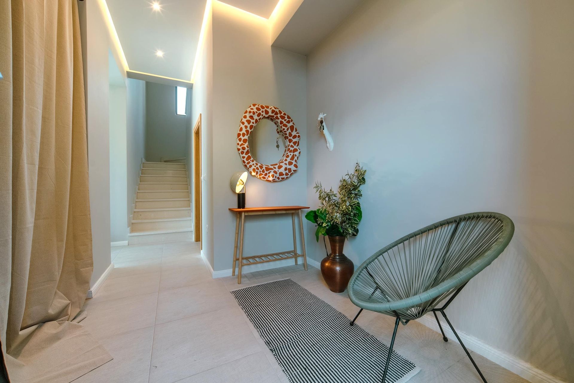 Modern hallway interior in a villa in Krašići, Montenegro: designer mirror, console table, and wicker armchair.
