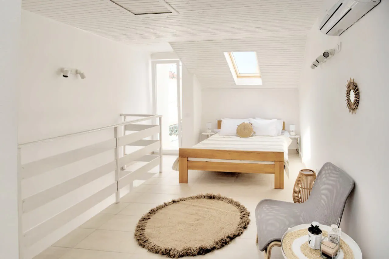Bright bedroom with a wooden bed, skylight, white walls, and a round rug.