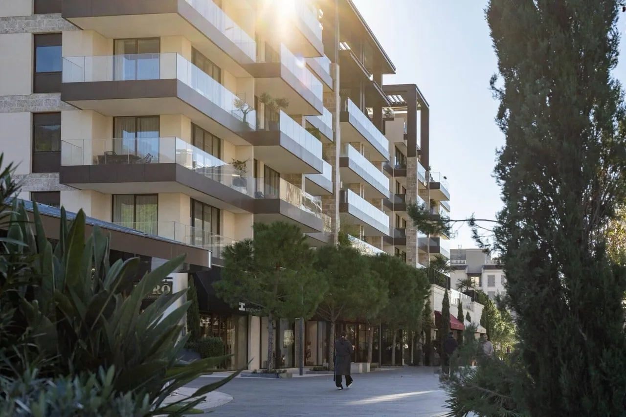 Exterior view of a modern multi-story residential building with balconies and a landscaped pedestrian walkway.