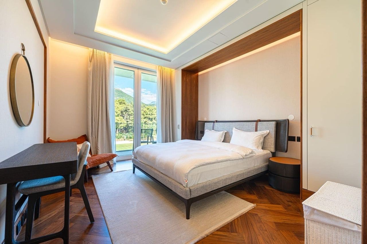 Modern bedroom in Porto Montenegro, Tivat, Montenegro: double bed, parquet flooring, and mountain view from the window.