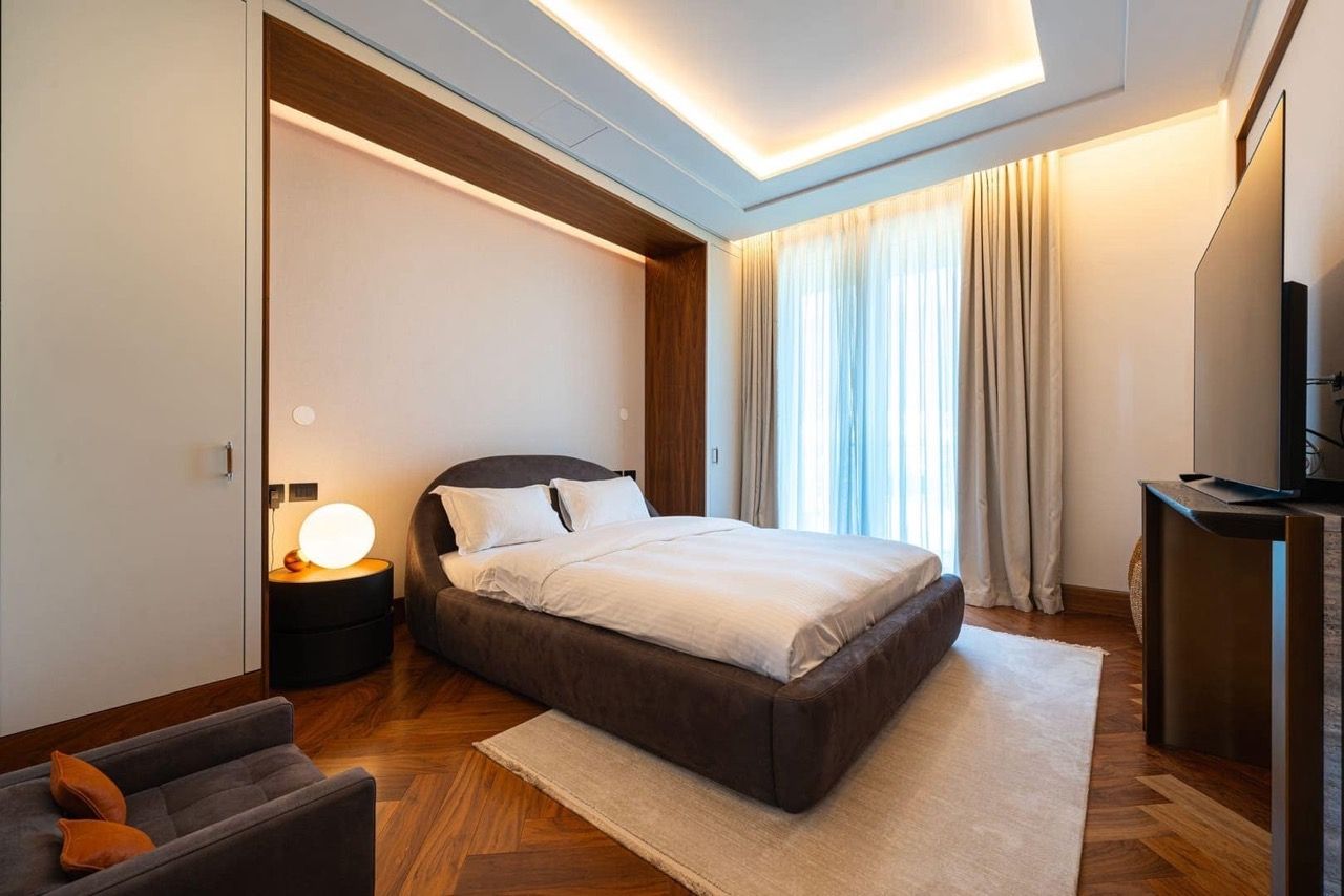 Modern bedroom in an apartment in Porto Montenegro, Tivat, Montenegro: double bed, parquet flooring, and panoramic windows.