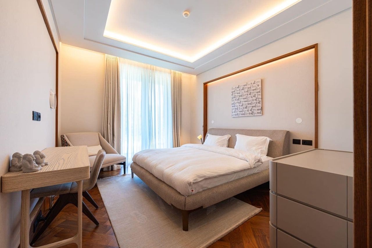 Modern bedroom in an apartment in Porto Montenegro, Tivat, Montenegro: double bed, desk, and view of the terrace.