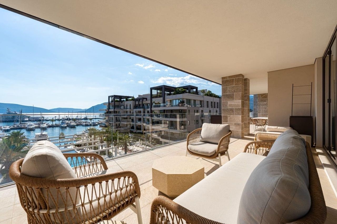 Terrace with wicker furniture and a view of Porto Montenegro marina, Tivat, Montenegro. Luxury apartments with a yacht panorama.