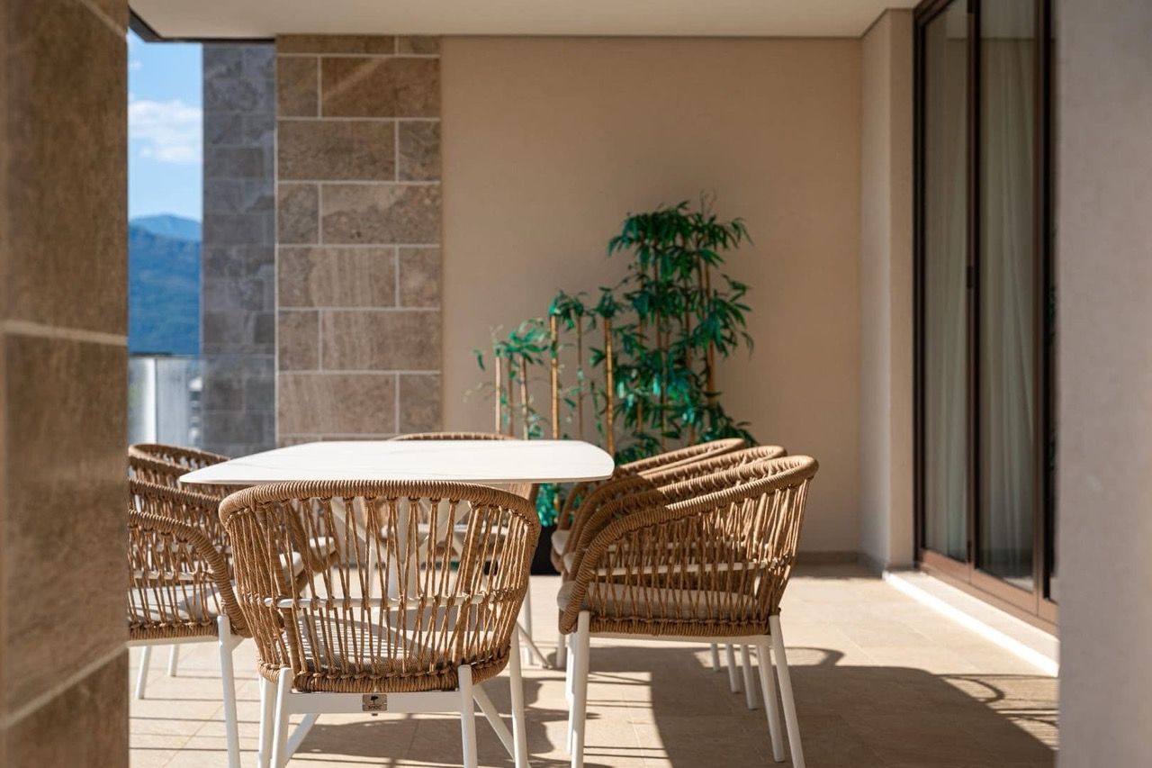 Cozy terrace with wicker furniture in an apartment in Porto Montenegro, Tivat, Montenegro, with mountain views and stone finishes.