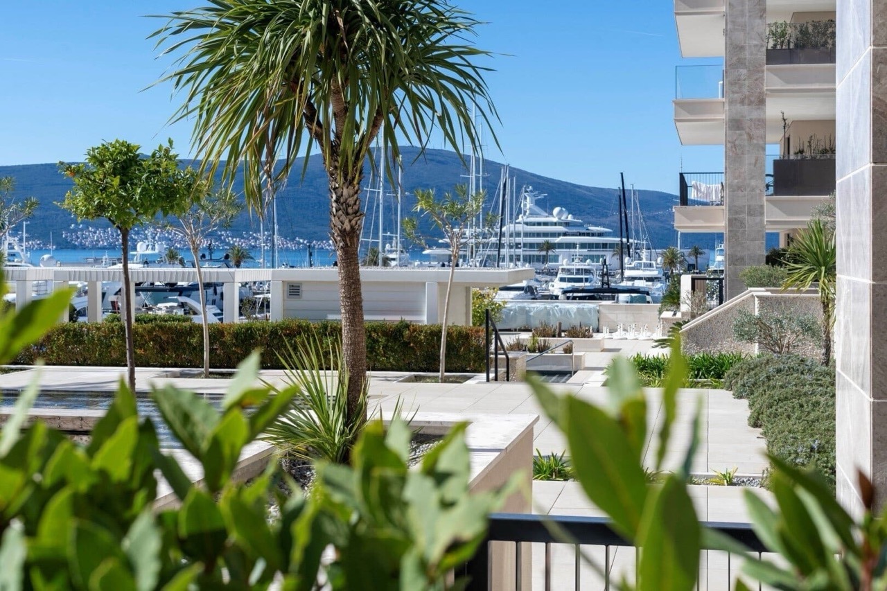 View of the marina and yachts from a luxury residential complex in Porto Montenegro, Tivat, Montenegro, with a landscaped terrace.