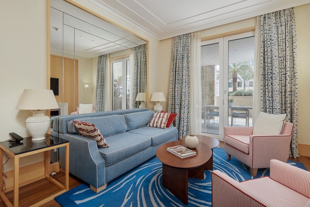 Living room in an apartment in Porto Montenegro, Tivat, Montenegro: blue sofa, armchairs, coffee table, and access to the terrace.