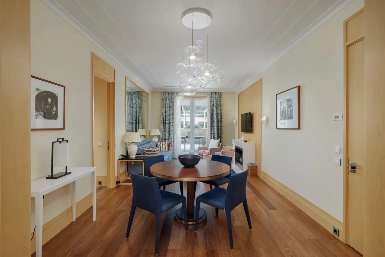 Living room featuring a round dining table, blue chairs, sofa, fireplace, and TV on wood floors.