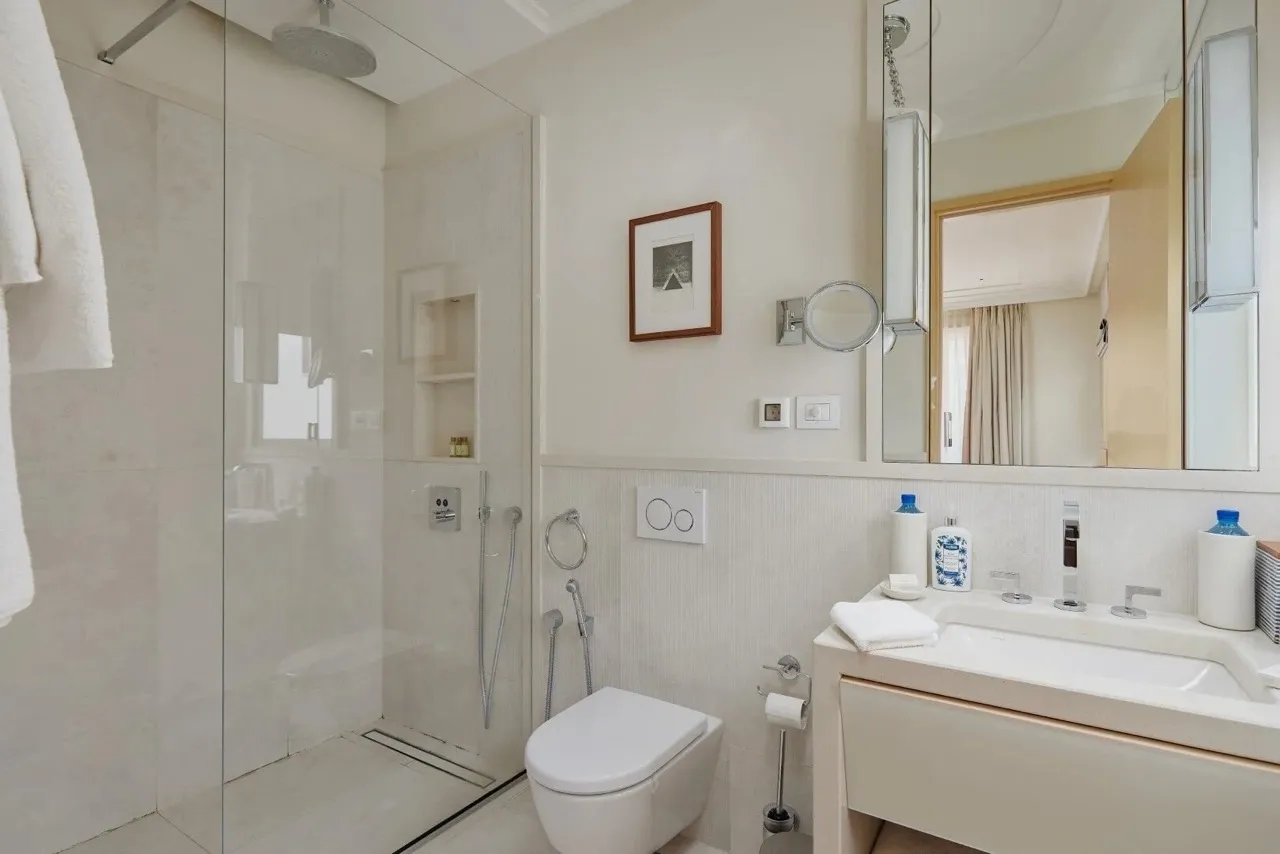 Modern bathroom featuring a glass shower enclosure, wall-mounted toilet, and vanity sink.