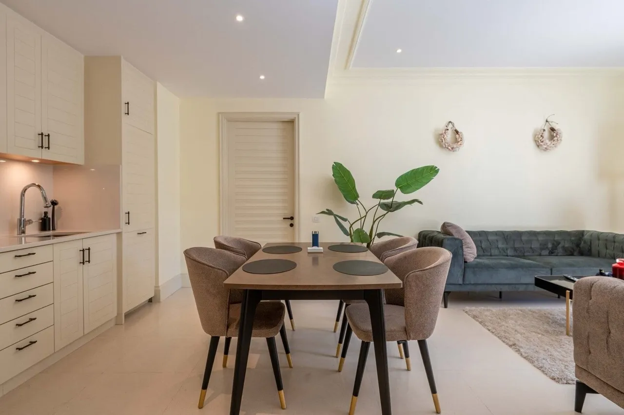 Open plan space featuring kitchen cabinets, a dining table with chairs, and a living area sofa.