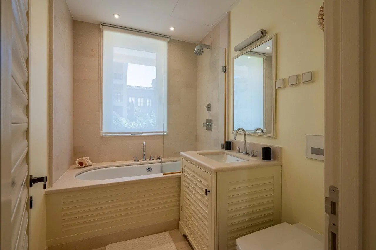 Bathroom featuring a bathtub, vanity sink, shower fixture, and wall mirror.