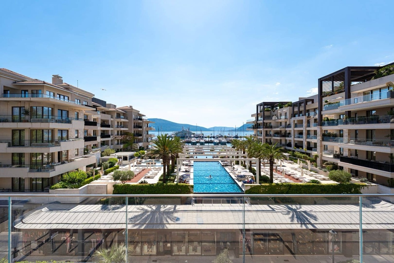 View of the luxury Porto Montenegro residential complex in Tivat, Montenegro: pool, yacht marina, and apartment terraces.