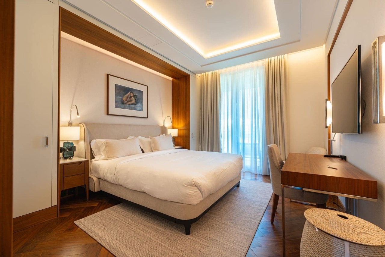 Modern bedroom in Porto Montenegro apartments, Tivat, Montenegro: double bed, desk, and parquet flooring.