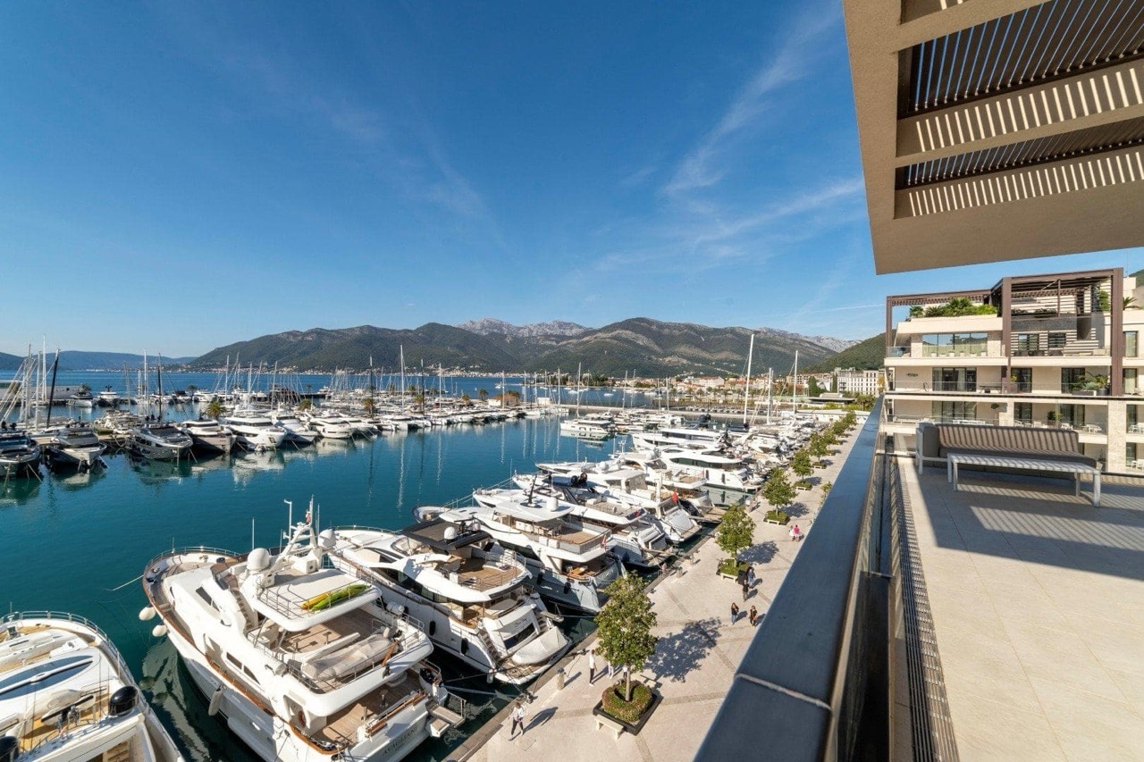 View from the apartment terrace in Porto Montenegro, Tivat, Montenegro: a panorama of the yacht marina and mountains against the sea.