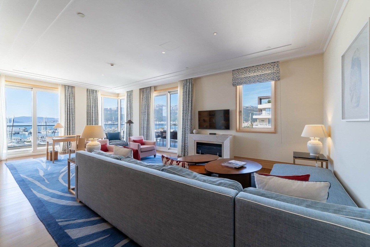 Living room with a view of the marina in Porto Montenegro, Tivat: modern furniture, a fireplace, and panoramic windows in Montenegro.