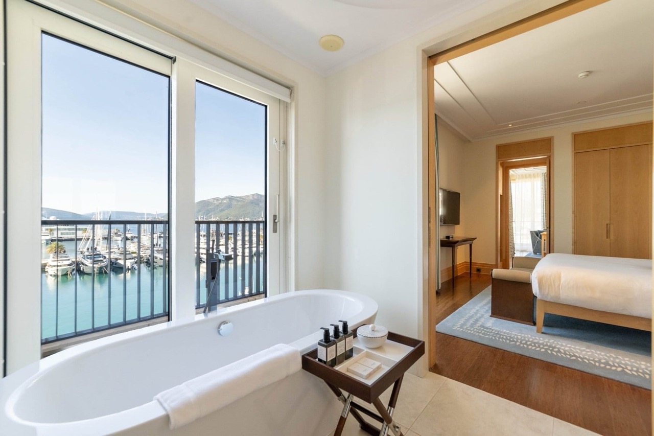 Bathroom with a view of the marina in Porto Montenegro apartments, Tivat, Montenegro: bathtub and bedroom interior.