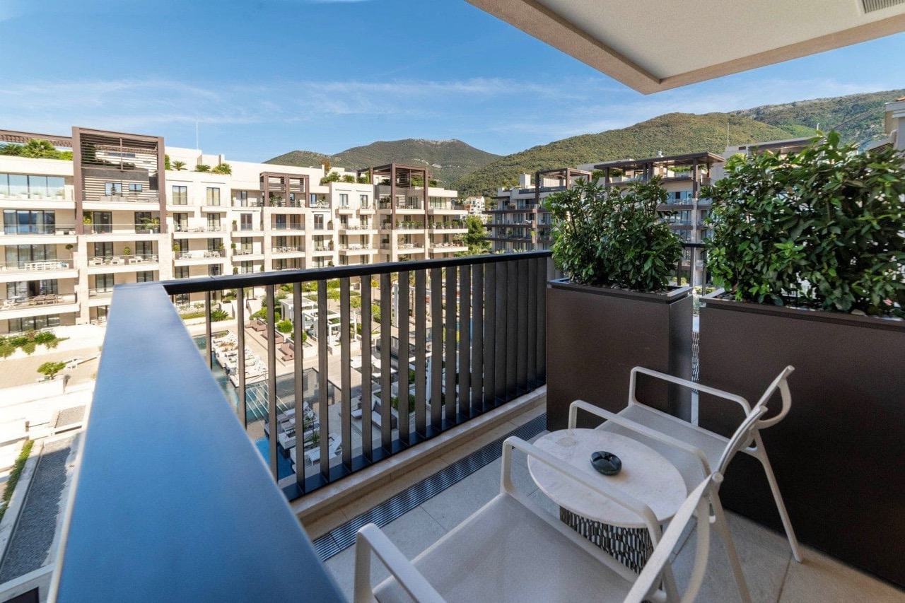 Balcony with furniture in the premium Porto Montenegro residential complex, Tivat, Montenegro: view of the pool and mountains from a modern apartment.