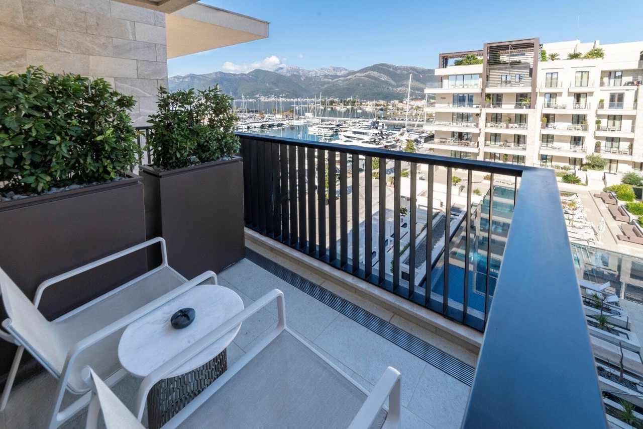 Balcony with furniture in Porto Montenegro, Tivat, Montenegro: view of the yacht marina, mountains, and the residential complex pool.