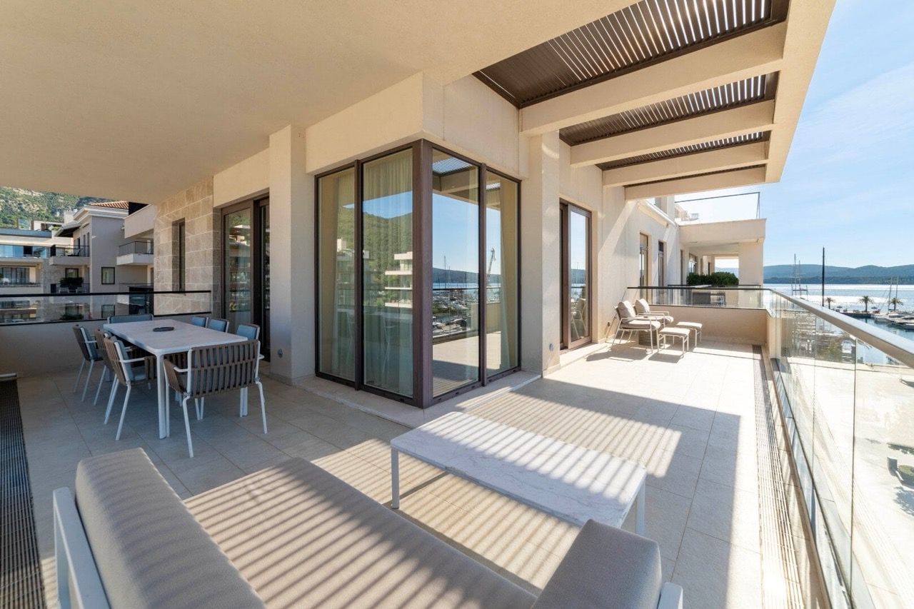 Spacious terrace with furniture and views of the marina in Porto Montenegro, Tivat, Montenegro: dining area and lounge area.