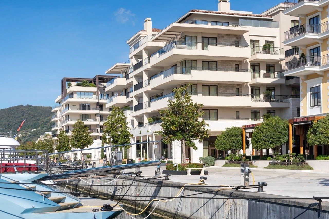 Modern residential complex in Porto Montenegro, Tivat, Montenegro, overlooking the waterfront promenade and moored yachts.