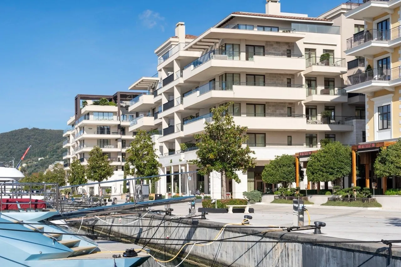 View of multi-story residential buildings with balconies located at a marina with boats in the foreground.