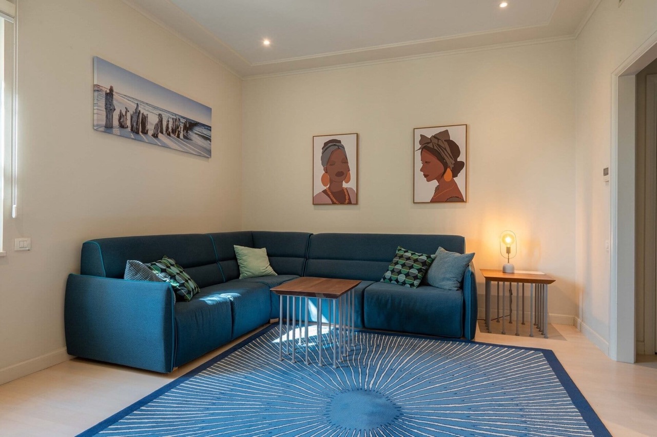 Cozy living room in an apartment in Porto Montenegro, Tivat, Montenegro: blue corner sofa, stylish rug, and wall decor.