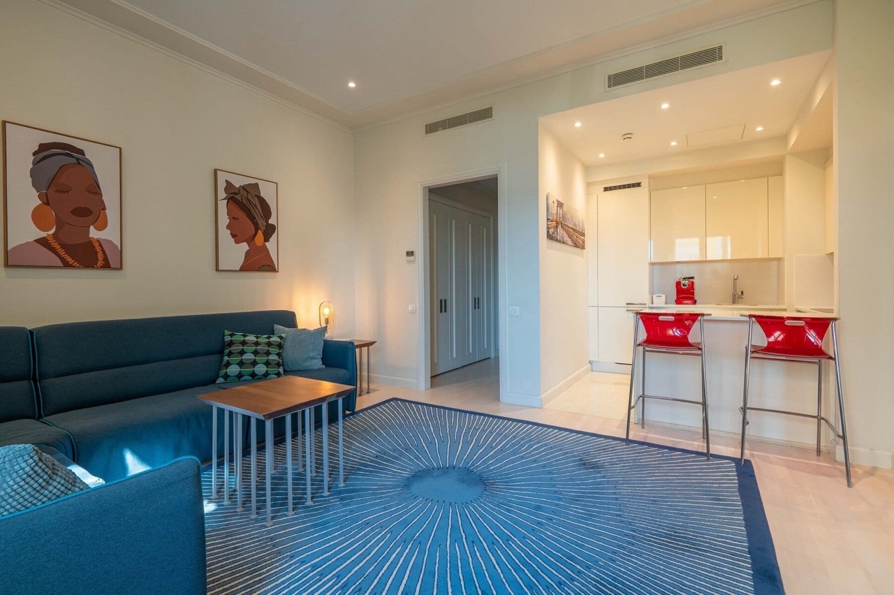 Modern living room with kitchen in Porto Montenegro apartments, Tivat, Montenegro: blue sofa and stylish interior.