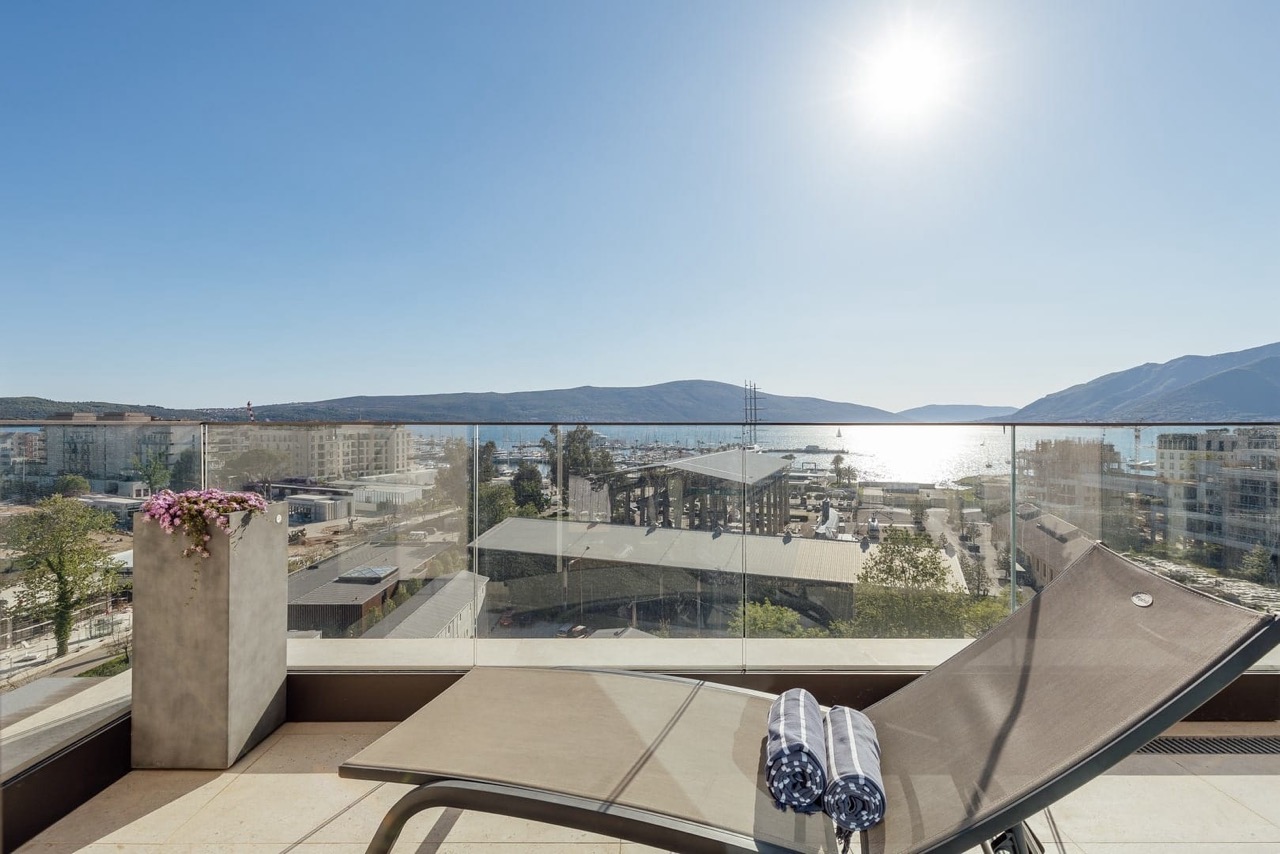 Terrace with a sun lounger and a view of Porto Montenegro marina, Tivat, Montenegro. Panoramic view of the sea and mountains.