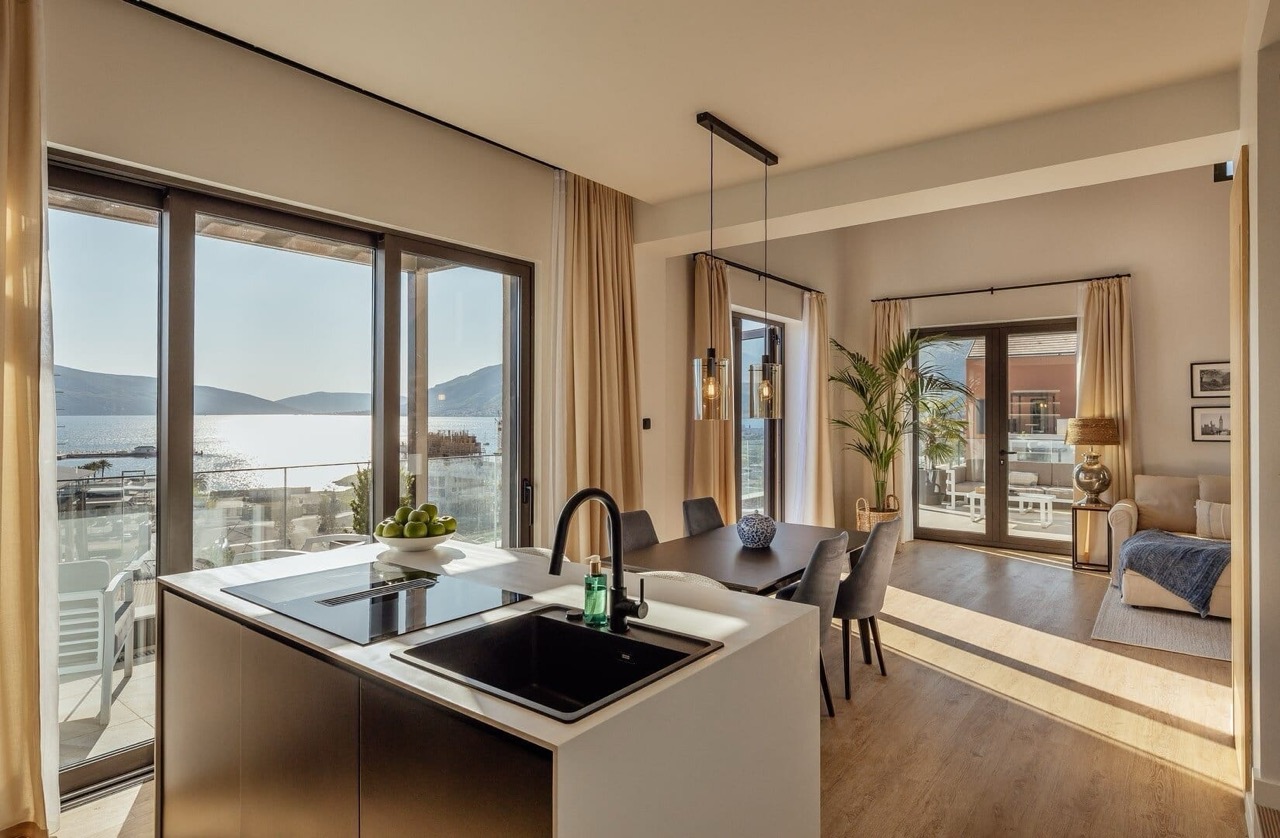 Modern kitchen-living room with sea view in Porto Montenegro, Tivat, Montenegro: island, dining area, and terrace.