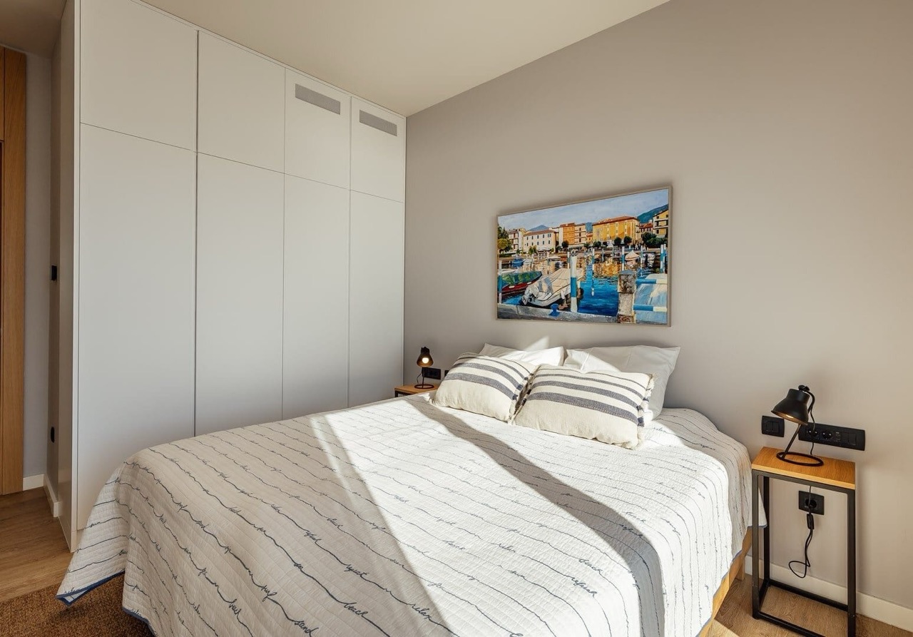 Modern bedroom in an apartment in Porto Montenegro, Tivat, Montenegro: double bed, built-in wardrobe, and decor.