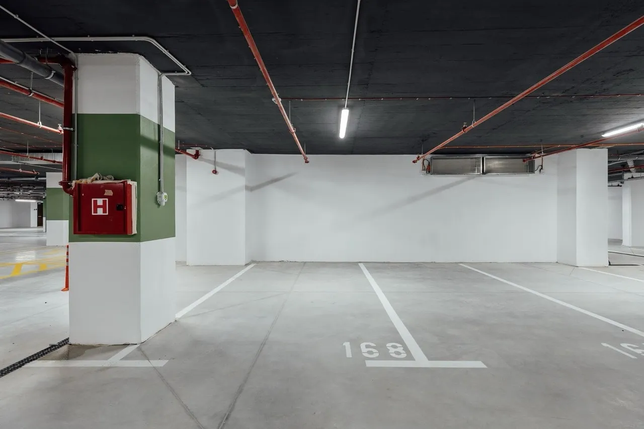 Underground parking space marked 168, featuring a column with a fire hose cabinet and red pipes on the ceiling.
