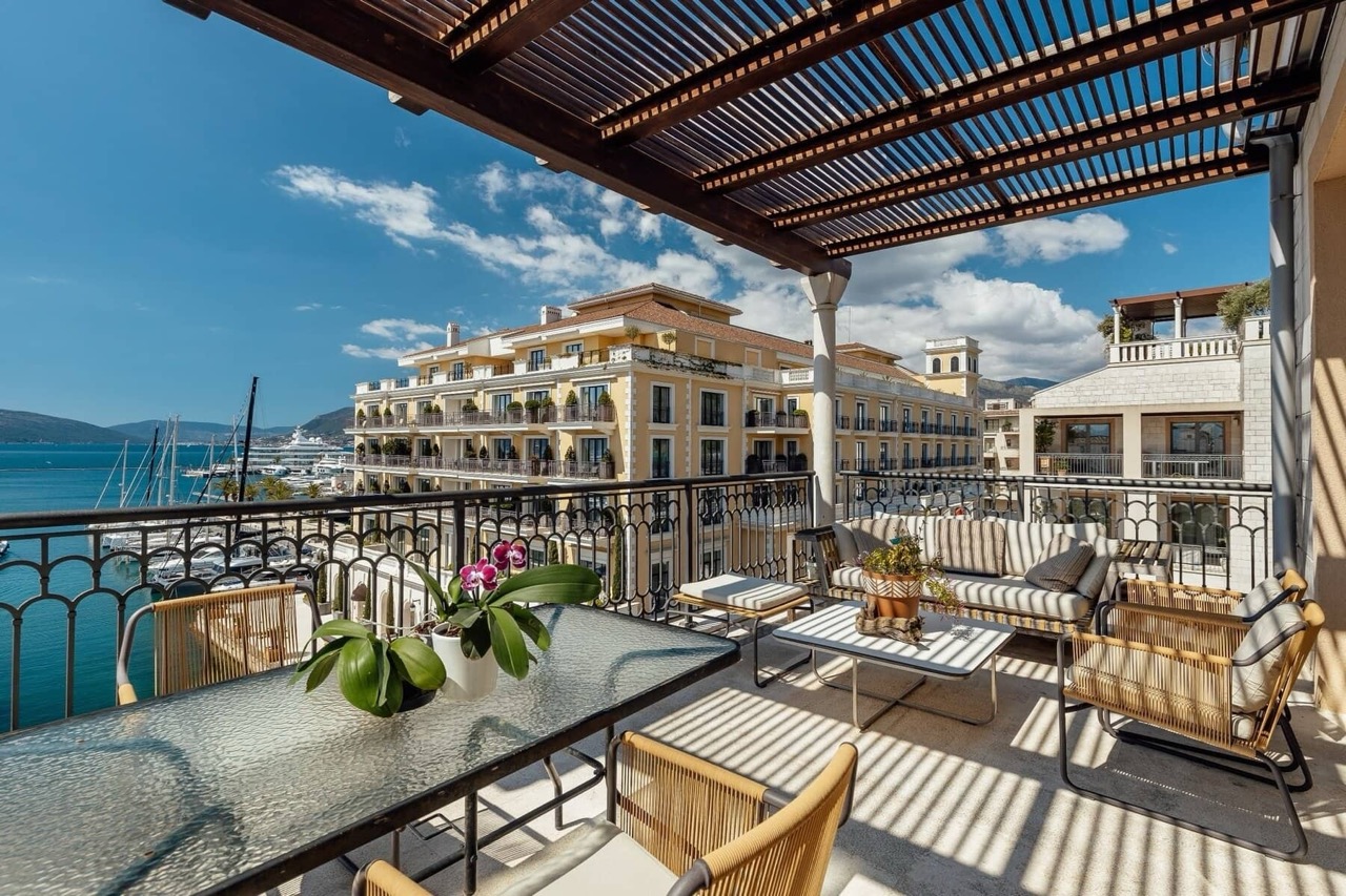 Terrace with furniture in Porto Montenegro, Tivat, Montenegro: view of the marina, yachts, and the Regent hotel from the apartment balcony.