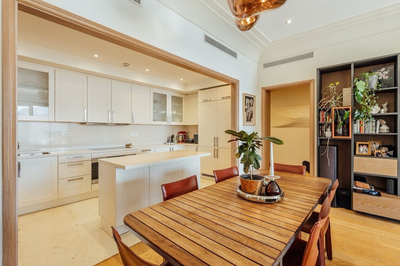 Modern kitchen-dining room in an apartment in Porto Montenegro, Tivat, Montenegro: light cabinetry, an island, and a dining table.