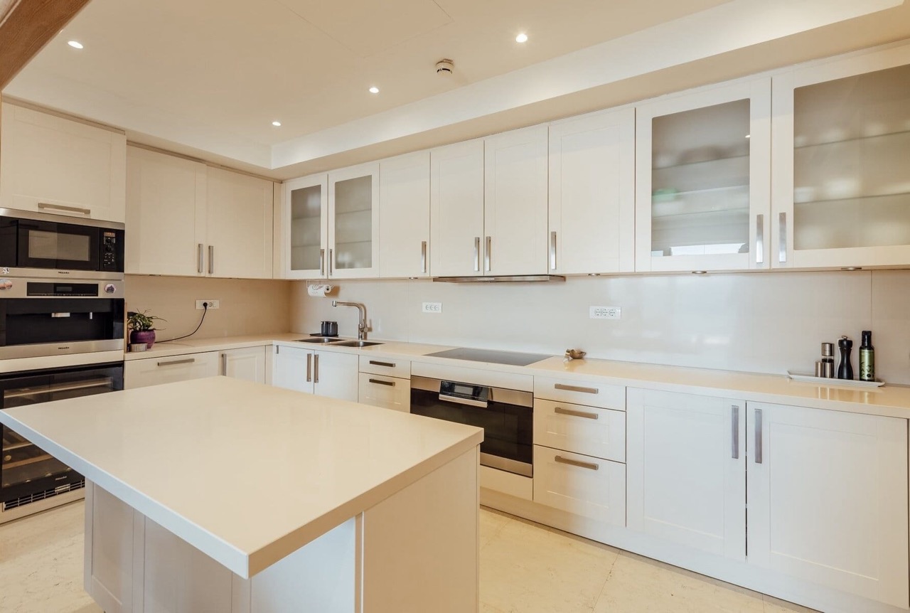 Modern white kitchen with island and Miele appliances in an apartment in Porto Montenegro, Tivat, Montenegro.