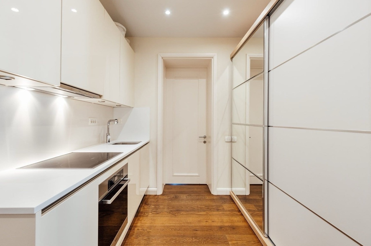 Modern white kitchen with a mirrored cabinet in an apartment in Porto Montenegro, Tivat, Montenegro.